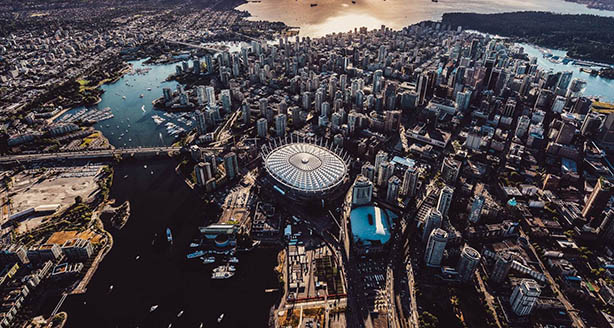 Aerial view of BC Place stadium in Vancouver surrounded by the city skyline and waterfront at sunset.